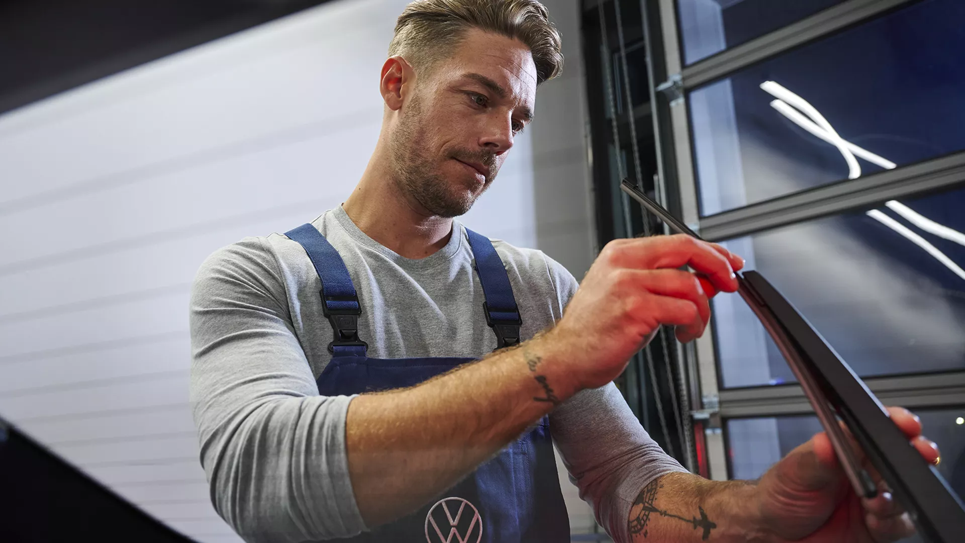 Vista di un meccanico Volkswagen mentre esegue il check di un componente di un'auto e di una donna montare il box per il tetto.